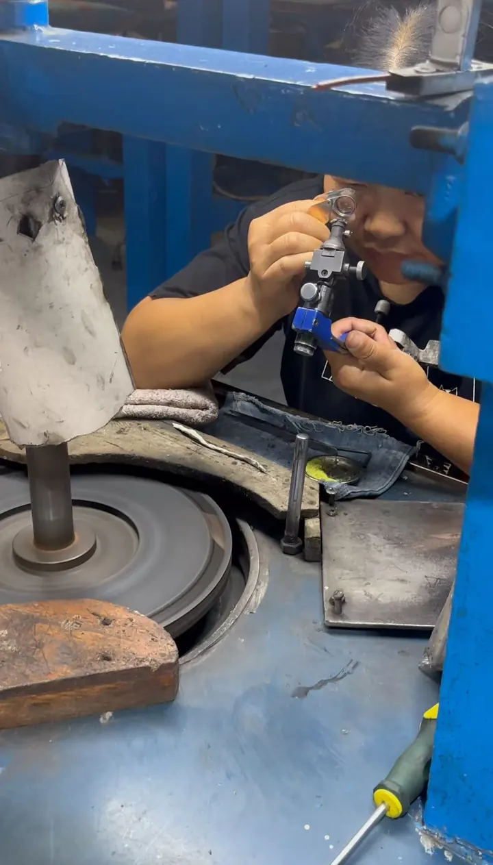 Jewelry craftsperson polishing a piece at a workbench.