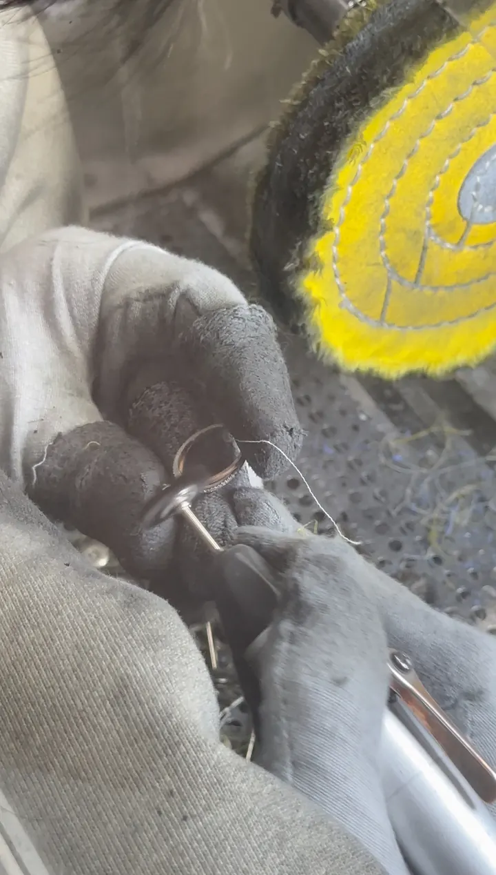 Close-up of jewelry setting work beside a polishing wheel.